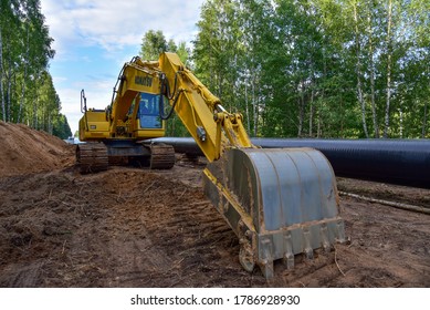 Yellow Excavator KOMATSU During Earthwork For Laying Crude Oil And Natural Gas Pipeline In Forest Area. Installation Petrochemical Pipe. Minsk Region, Belarus, JUL 24. 2020