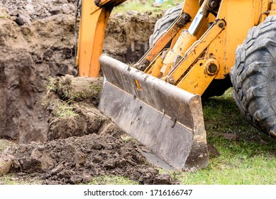 Yellow excavator on a construction site against blue sky. The modern excavator performs excavation work on the construction site - Shutterstock ID 1716166747
