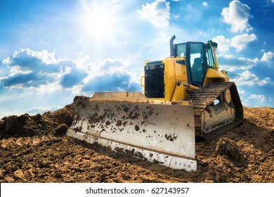 Yellow excavator on new construction site, with the bright sun and nice blue sky in the background - Shutterstock ID 627143957