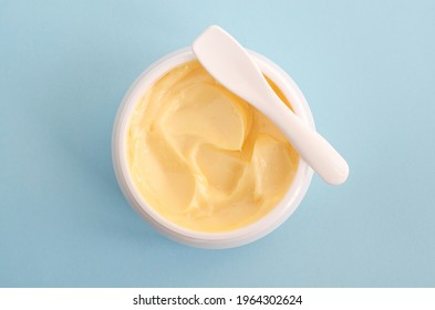 Yellow facial mask (banana face cream, shea butter hair mask, body butter). Natural skin and hair concept. Light blue background. Top view, copy space.