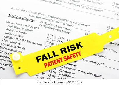 A yellow fall risk patient  safety bracelet on top of a hospital questionnaire paperwork