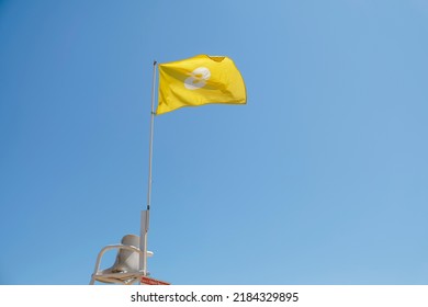 Yellow flag on the beach at the lifeguard's ladder to alert bathers that bathing is only allowed if you are standing on the sand with your head out of the water. Beach safety concept. yellow flag - Powered by Shutterstock