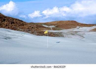 yellow flag on a snow covered links golf course in ireland in winter