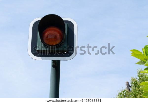 Yellow flashing orange traffic light signal
for cars blue sky
background