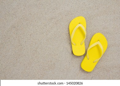 yellow flip flops laying on the sandy beach - Powered by Shutterstock