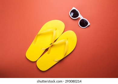 Yellow flip flops and sunglasses on a red wooden background - Powered by Shutterstock