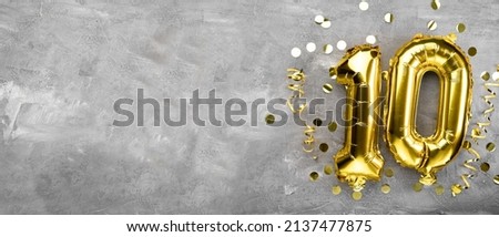 Yellow foil balloon number, number ten on a concrete background. 10th birthday card. Anniversary concept. for anniversary, birthday, new year celebration. banner, copy space.