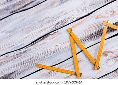 Yellow folding ruler on gray wooden background.