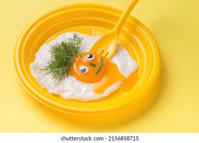 A Yellow Fork Piercing A Fried Egg Face In A Yellow Plate. Minimal Concept. A Popular Breakfast. Flat Lay.