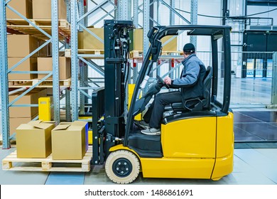 Yellow Forklift Close-up. A Man Operates A Forklift. Move Crates On Pallets Throughout The Warehouse. Warehousing Business. Warehouse Logistics. Storage Of Goods.