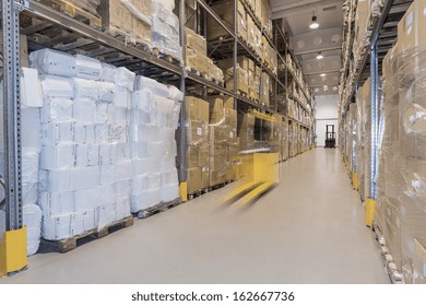 Yellow forklift moving in huge spacious warehouse