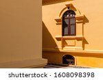 Yellow French Colonial building facade and artisan window frame high contrast light and shadow of summer