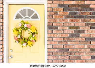 Yellow Front Door Of Vintage Brick House With Colorful Flower Wreath