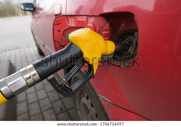 A yellow fueling gun is inserted into the\
vehicle tank. Close-up