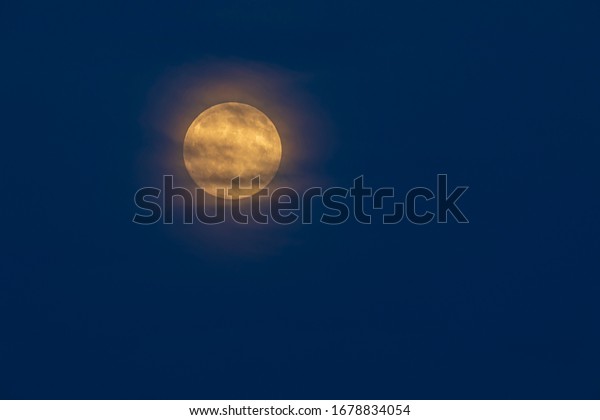 Yellow full\
moon with halo against a dark blue\
sky