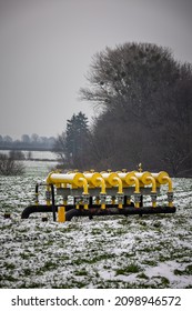 Yellow Gas Infrastructure Elements Sticking Out Of The Ground. Winter Photo Of A Snow-covered Gas Pipeline. High Natural Gas Prices. The Photo Was Taken On A Cloudy Day.