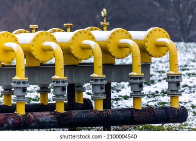 Yellow Gas Infrastructure Elements Sticking Out Of The Ground. Winter Photo Of A Snow-covered Gas Pipeline. High Natural Gas Prices. The Photo Was Taken On A Cloudy Day.