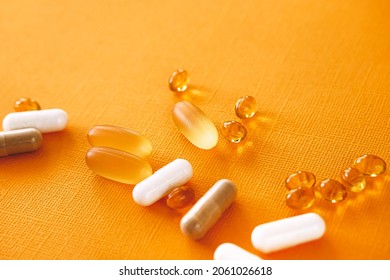 Yellow gel capsules of nutraceuticals in spoon. Pills and meds assortment.