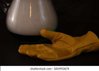 A Yellow Glove Next To Dry Ice Pitcher On Black Background