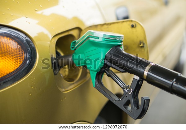 Yellow,\
gold car at a gas station being filled with\
fuel