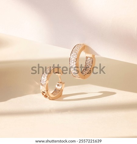 Yellow gold hoop earrings encrusted with small diamonds, showcasing a simple and elegant design.
