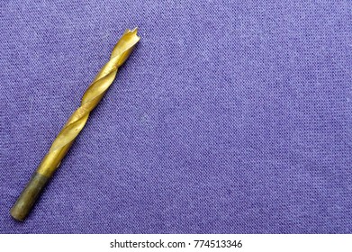 Yellow, Golden, Copper Drill On Wood On A Background Of Purple Cloth. Drill For A Drill Or Perforator.