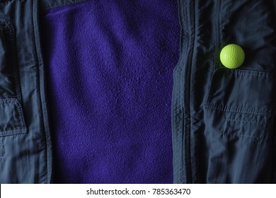 Yellow Golf Ball On Open Green Jacket With  Blue Lining, Like A Ball Lying At The Edge Of A Water Hazard On A Golf Course