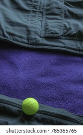 Yellow Golf Ball On Open Green Jacket With Blue Lining, Like A Ball Lying At The Edge Of A Water Hazard On A Golf Course