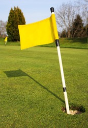 Yellow Golf Flag In Hole On Golf Course Green