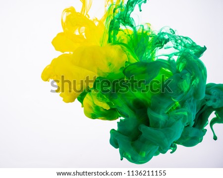 Yellow and green acrylic paint make an abstract explosion under water. Two ink colours mixing in liquid, isolated on white background. Yellow-green acrylic ink explosion under water