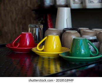 Yellow, Green , And Red Ceramic Coffee Cup Upside Down On Saucer On The Metal Shelf In Cafe.