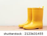 Yellow gumboots on wooden shelf. Yellow rain boots for spring or autumn rainy weather. Autumn fashion. Seasonal shopping and sales.