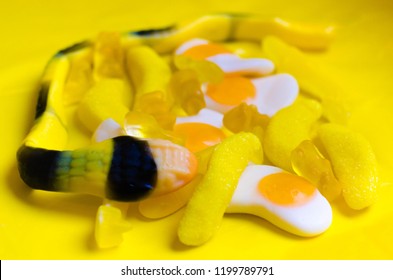 Yellow Gummy Candies On A Yellow Background. (bananas, Sharks, Fried Eggs, Snake, Bears) Close-up.