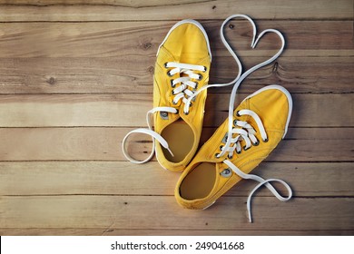 yellow gym shoes on a wooden floor, in which the laces are in the form of heart