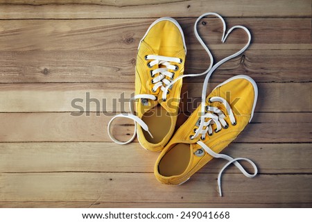 yellow gym shoes on a wooden floor, in which the laces are in the form of heart