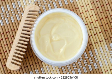Yellow hair mask (banana face cream, shea butter mask, mango body butter) in a small white container. Natural skin and hair treatment concept. Top view, copy space.