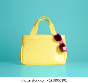Yellow handbag purse with pink sunglasses isolated on blue background.