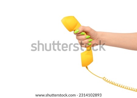 Yellow handset in woman hand with green nails isolated on a white background. Copy space.