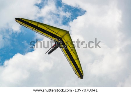 Yellow hang glider wing with cloudy sky on the background. Hangglider pilot and his aircraft.
