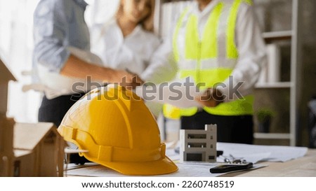 Yellow hard hat on workbench with Engineer teams meeting working together wear worker helmets hardhat on construction site. Asian industry professional team Stock photo © 
