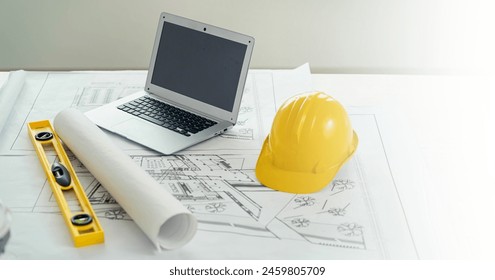 A yellow hard hat sits on top of a laptop computer. Concept of construction or engineering work, with the hard hat - Powered by Shutterstock