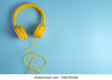 Yellow headphones on blue background. Music concept. - Shutterstock ID 1582781266