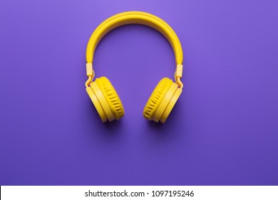 Yellow headphones on purple background. Music concept.