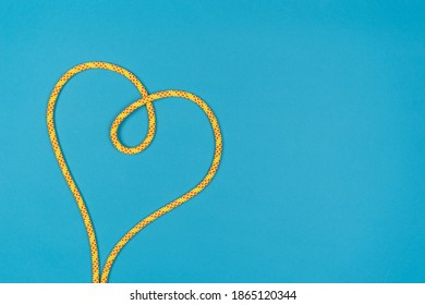 Yellow Heart With Climbing Rope On Blue Background