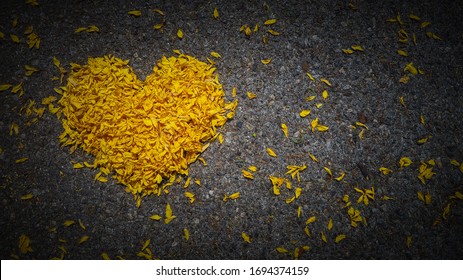 Yellow heart made of flower petals on dark background with space for text, heart shape, the concept of mourning, grief or sorrow.