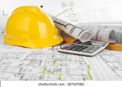 Yellow helmet, calculator, level and project drawings 