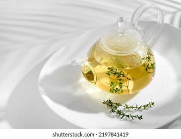 Yellow herbal tea with thyme in glass teapot. White background with copyspace. - Shutterstock ID 2197841419
