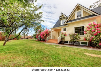 Yellow House Exterior With Spring Blooming Rhododendron