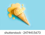 Yellow ice cream melting and spilling in waffle cone on pastel blue background. Minimal trendy creative summer food concept layout. Melted scoop of fruit mango icecream.