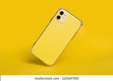 Yellow IPhone 11 In Clear Silicone Case Back View Falling Down Isolated On A Yellow Background. Transparent Phone Case Mock Up